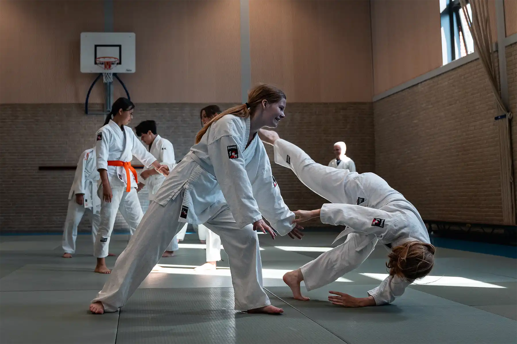 Kinderen oefenen samen aikido in een dojo en werken aan hun weerbaarheid, motoriek en zelfvertrouwen tijdens een aikido training.